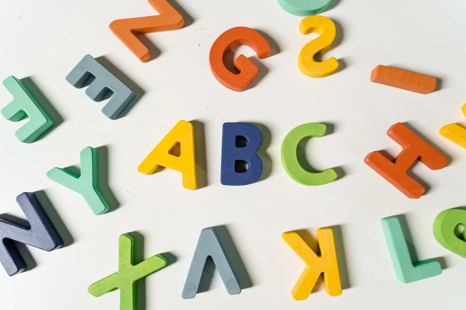 Letras coloridas de madeira espalhadas sobre uma superfície clara